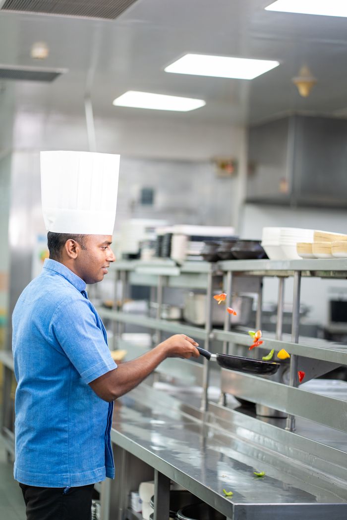 Chef skillfully cooking vegetables in a modern restaurant kitchen, emphasizing culinary expertise.